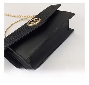 Detail shot of black leather flap bag with woven texture and gold M-logo metal buckle