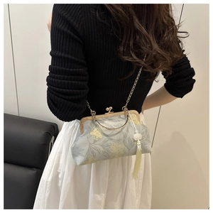 Close-up of vintage floral cheongsam bag with golden clasp and tassel on a female model