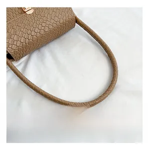 Detail of woven handle and crocodile pattern texture on a brown baguette shoulder bag