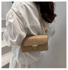 Detail of beige crocodile pattern bag featuring gold bamboo style twist lock buckle