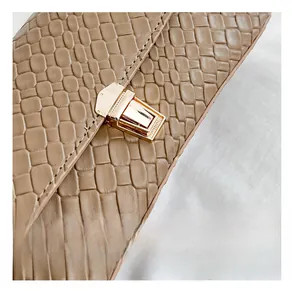 Detail of a brown woven texture bag featuring a golden rectangular twist lock closure