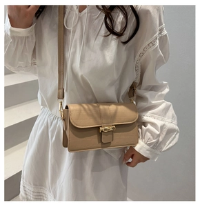 Dettaglio borsa beige con trama a coccodrillo e chiusura in bambù metallico dorato