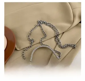 Detail showing the silver pleated handbag with a rhinestone handle and metal chain strap