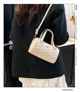 Detalle de bolso blanco acolchado con corazones y adorno de lazo plateado fino