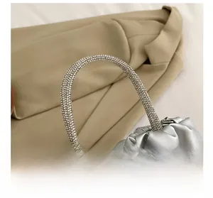 Detail showing the silver pleated leather bag with a sparkling rhinestone-embellished handle