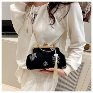 Detail of vintage black embroidery kiss-lock bag with white floral pattern and silk tassel