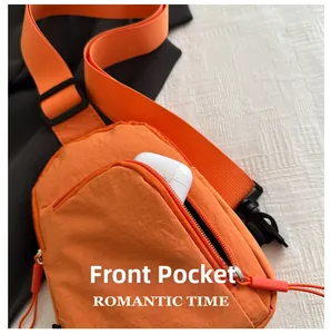 Détail de la poche zippée avant du sac bandoulière orange en nylon avec écouteurs sans fil