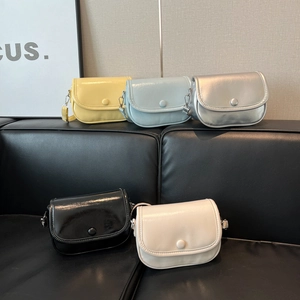 Minimalist PU leather semi-circular crossbody bags in five colors on a leather sofa
