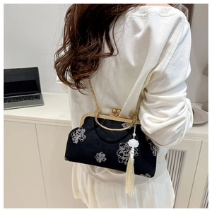 Detail of black velvet kiss-lock bag with white floral embroidery and tassel