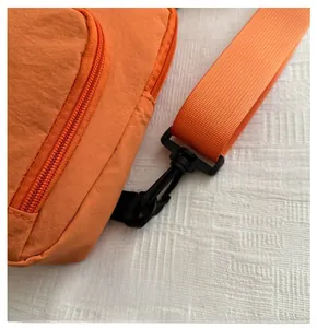 Détail du sac en nylon orange vif montrant le crochet en plastique noir et la bandoulière