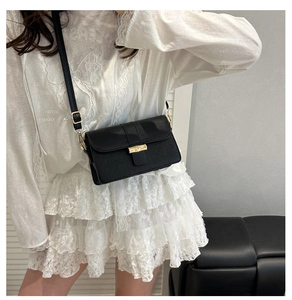 Detail of black faux crocodile leather crossbody bag with vintage golden metal buckle