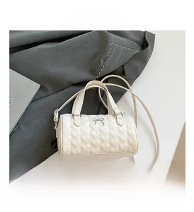 Detalle del bolso Boston cilíndrico blanco con acolchado de corazones y lazo de metal