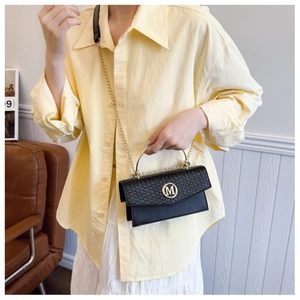 Detail of woven texture shoulder bag with gold M logo and chain strap on a model