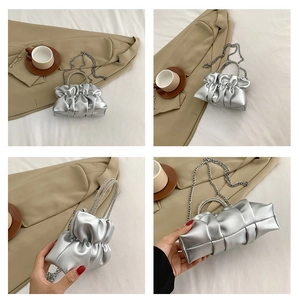 Macro view of silver pleated cloud bag featuring rhinestone handle and metal chain strap