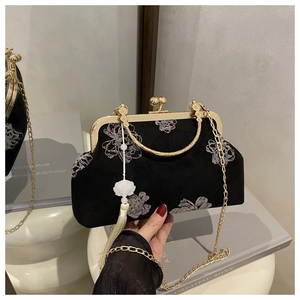 Close-up of black velvet evening bag with floral embroidery and golden metal hardware