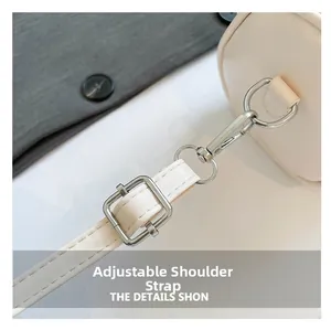 Detalle de la correa ajustable de cuero con ganchos de metal plateado en un bolso blanco