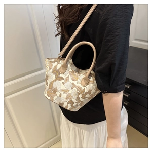 Floral embroidery handbag detail with beige leather handles shown on a model outfit
