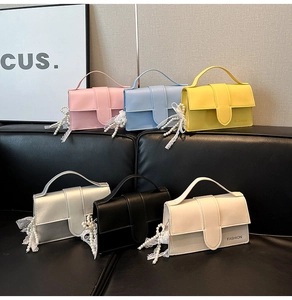Detail view of colorful faux leather crossbody bags with pearl and lace bow pendants