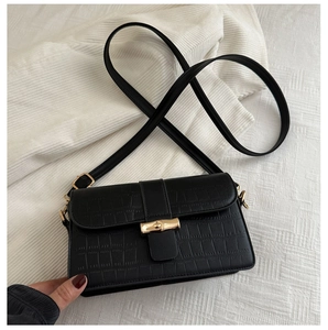 Close-up of black crocodile pattern leather bag with golden bamboo buckle detail