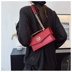 Close-up of red textured leather crossbody bag with gold M logo and chain strap details