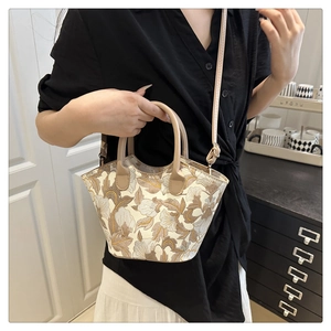 Detailed embroidery of yellow flowers on a cream tote bag with leather handles