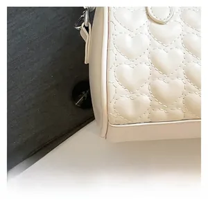 Vista detallada del bolso beige de cuero sintético con costuras acolchadas en forma de corazón