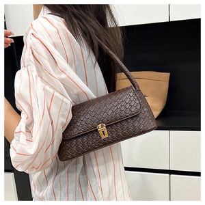 Detail of dark coffee baguette bag showing weave texture and gold buckle on shoulder