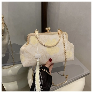 Detail view of vintage cream floral handbag with gold frame and white tassel charm