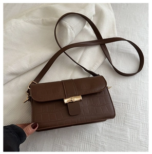 Close-up of brown crocodile texture handbag with a golden bamboo-style twist lock