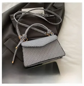 Détail d'un sac à main monogramme sur un costume avec sa bandoulière et son rabat chic