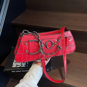 Red crocodile texture shoulder bag with silver metal ring and chain on wooden background