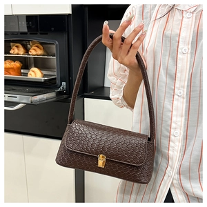 Detail of dark brown woven texture shoulder bag with rectangle gold clasp and lock