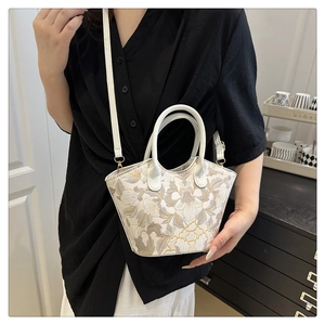 Detail view of floral embroidered white leather handbag with adjustable crossbody strap