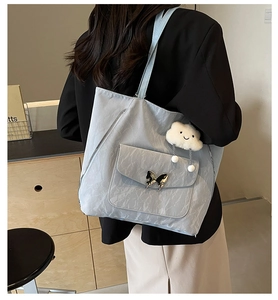 Detail of light blue tote bag with butterfly metal clasp and cloud plush charm
