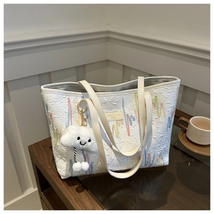 Detailweergave van een grote witte shopper met kleurrijk borduursel en een schattige wolkhanger