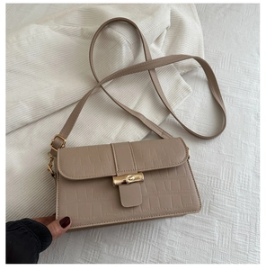 Detail of light khaki crocodile pattern handbag with elegant golden bamboo buckle closure