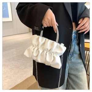 Detailed view of white pleated cloud bag featuring a sparkling rhinestone handle and chain strap