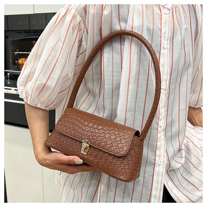 Detail of brown woven texture and gold clasp on elegant faux leather baguette bag