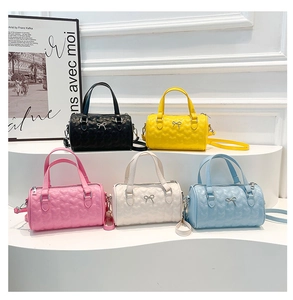 Detail of five colorful mini boston bags with heart quilting and bow metal buckles