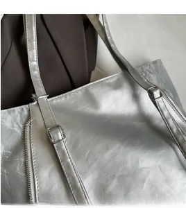 Detail of silver tote bag showing metallic crinkled texture and adjustable long strap
