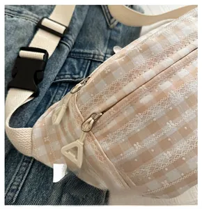 Close-up of smooth double zipper on orange gingham chest bag with delicate lace trim
