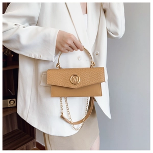 Detail of camel crossbody bag featuring woven texture and golden M-logo metal clasp