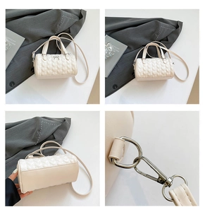 Detalle de bolso cilíndrico crema con acolchado de corazón y lazo metálico plateado