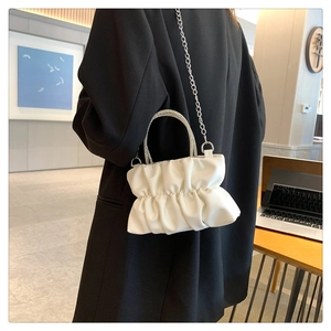 Detail of white pleated cloud bag with rhinestone handle and silver metal chain strap