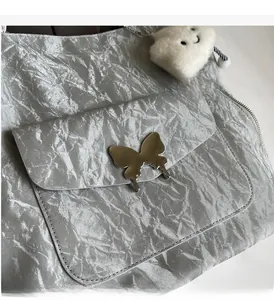 Detail of silver tote bag with metallic pleated texture and butterfly metal buckle