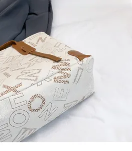 Close-up of white tote bag showing lychee grain texture and detailed logo embroidery