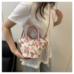 Detailed embroidery of floral patterns on an elegant trapezoid hobo bag with pink straps
