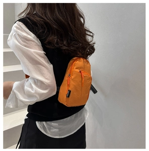Dettaglio del marsupio in nylon arancione acceso con cerniera ed etichetta in tessuto
