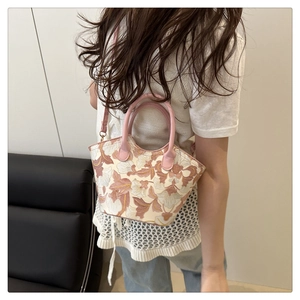 Detail of floral embroidered bucket bag with pink leather handles and cross-body strap