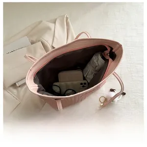 Interior capacity of pink woven tote bag showing daily essentials and zip pocket